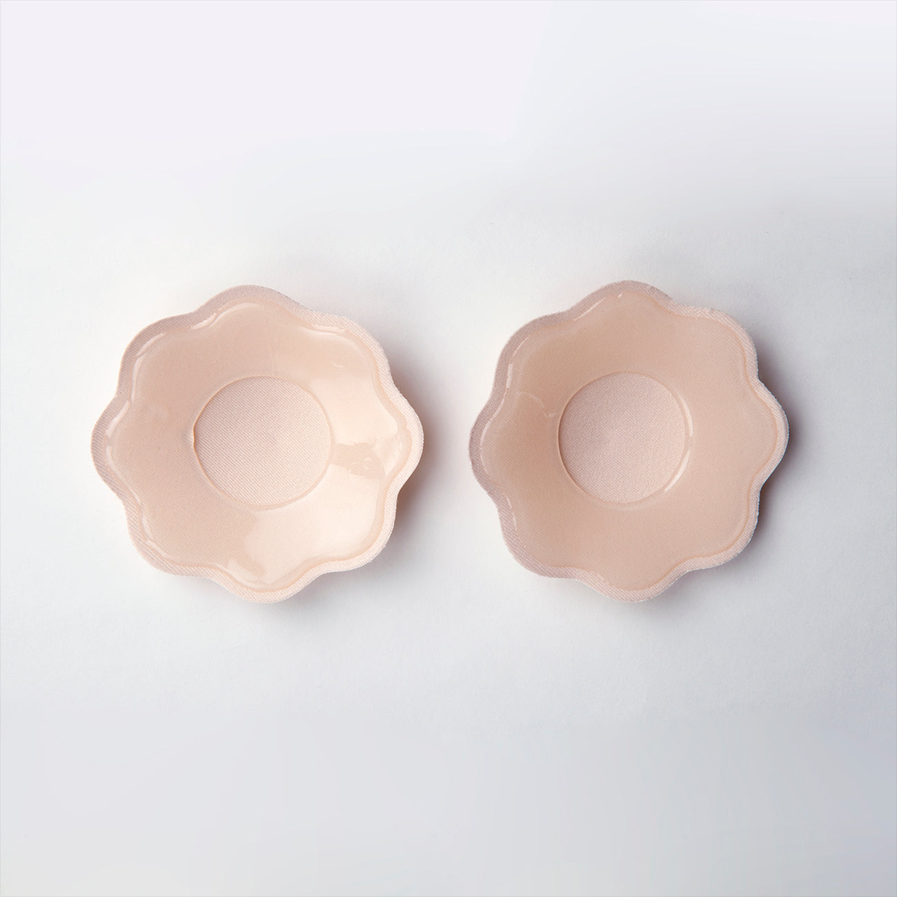 An image showing the back of the water resistant petals. The adhesive is around the edges and leaves a small soft and non-adhesive center for the nipple. Petals are nude in color.