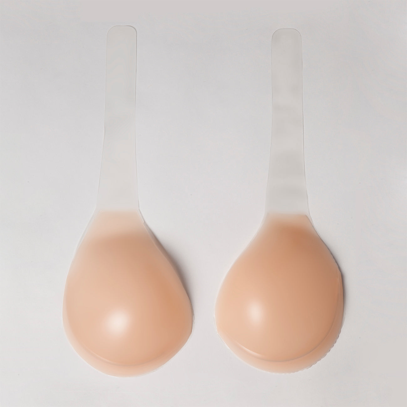 Product image of the voluptuous silicone lift. they are two separate cups with long adhesive strips to wrap up to the shoulders for lift. The cups are opaque nude, thick, and strong.
