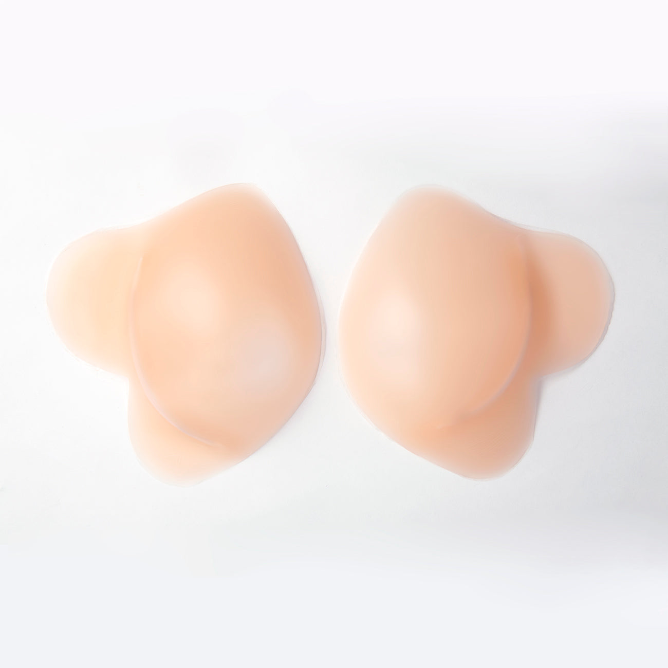 Le lusion second skin product image, not on model. It has an oval shaped exterior and has shaped cups. The inside is facing down and the outside is facing the viewer. Bra is mildly transparent nude.
