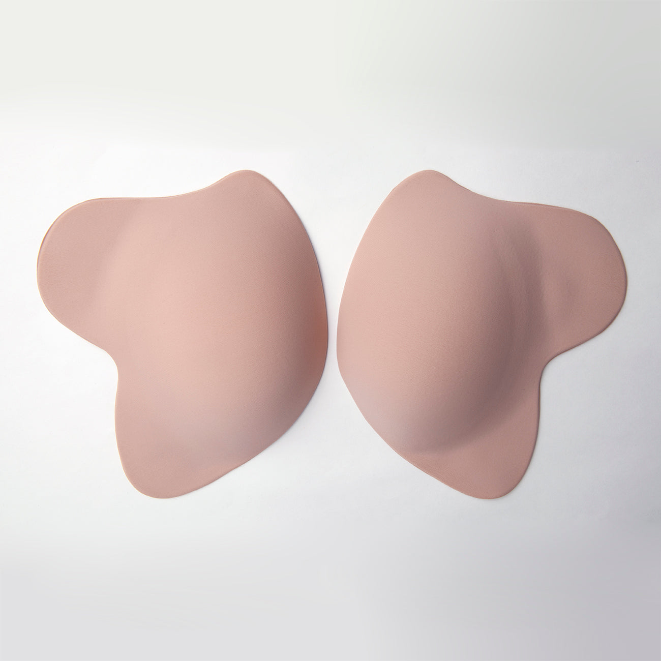 Outside view of the le lusion, inside facing down. It has an oval shape with flaps on the side for support. Bra is light tan in color.