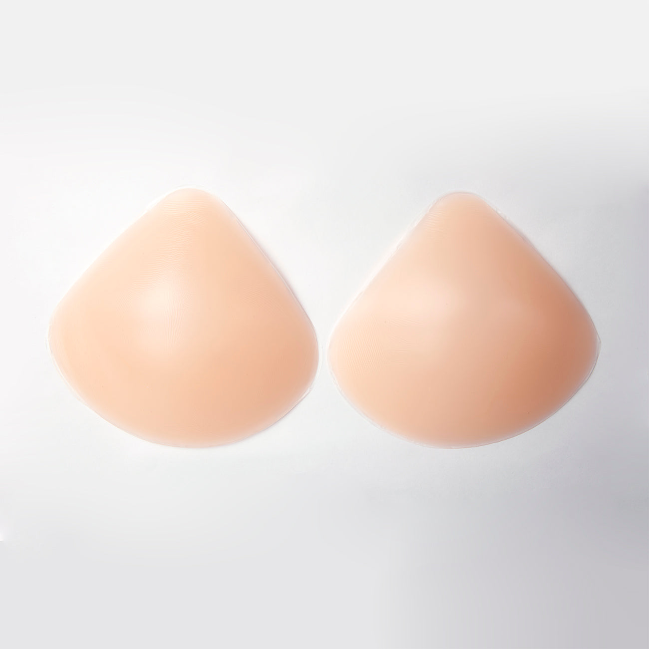 Product image of the lift it up backless strapless plunge bra from the outside. The bra is shaped and opaque. They are in a wide teardrop shape. almost a triangle with a curved base. There are two separate cups. Bra is nude in color.